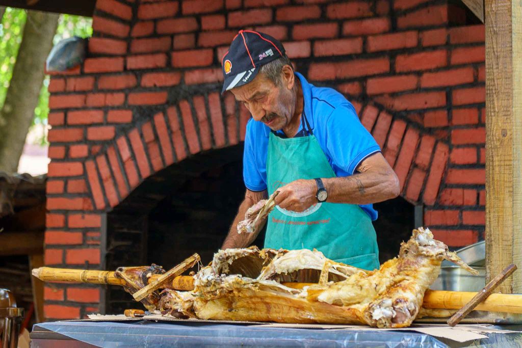 A local man preparing grilled pork during a summer street festival in Ardino, Bulgaria.