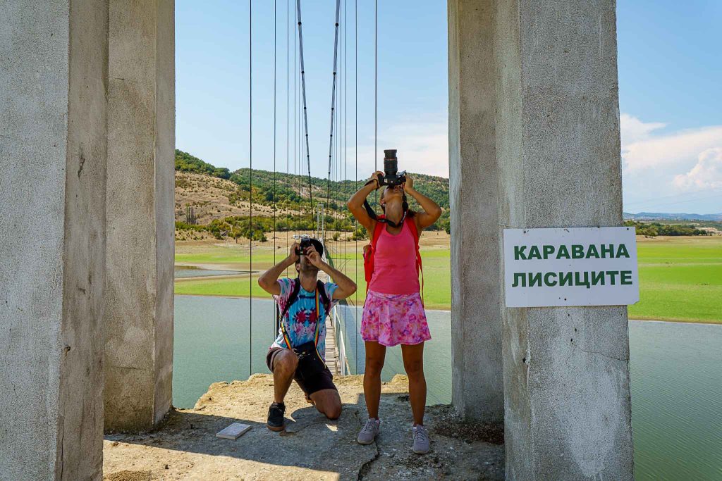 Two photographers capturing the view from a suspension bridge at Каравана Лисиците in Kardzhali, Bulgaria.
