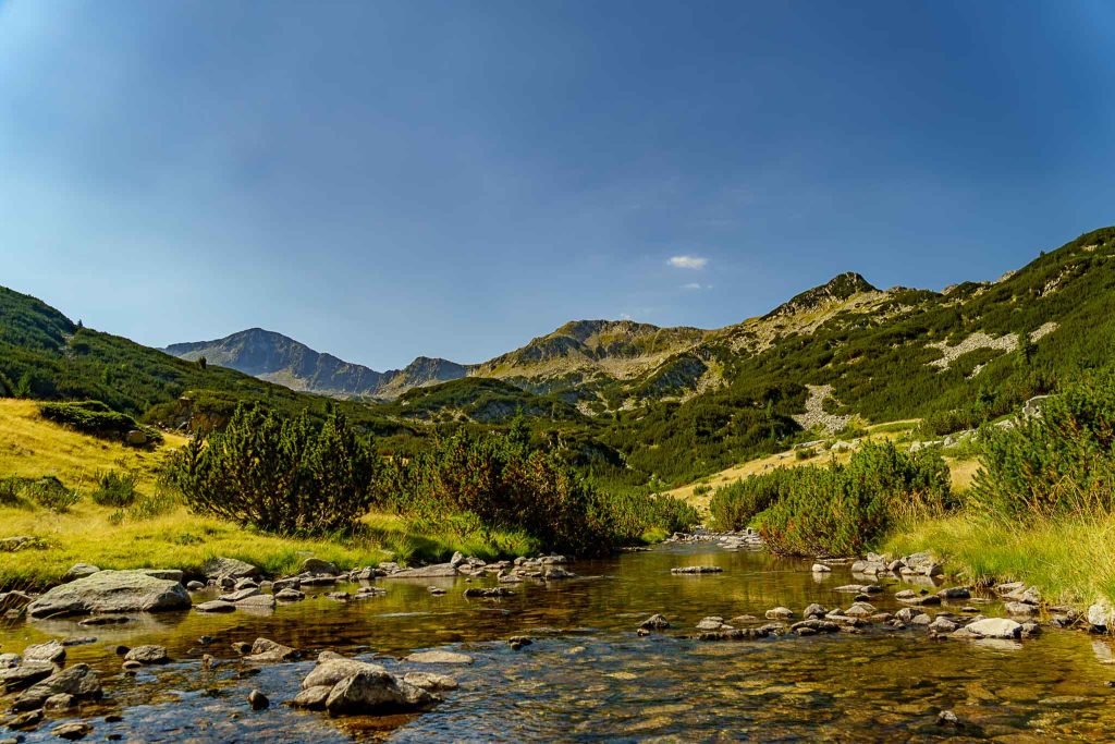 A quiet creek in the foreground and rugged mountain peaks in the background, Pirin Mountains, Bulgaria.