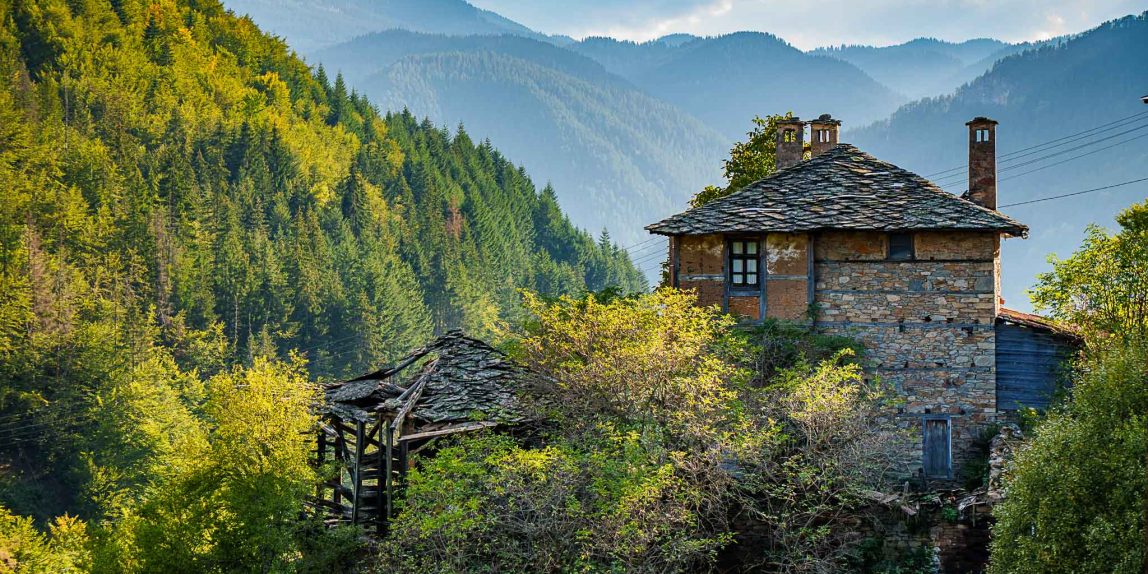 Traditional stone house in the Rhodope Mountains, Bulgaria, surrounded by mist and forest — captured during a quiet morning on a photography tour.