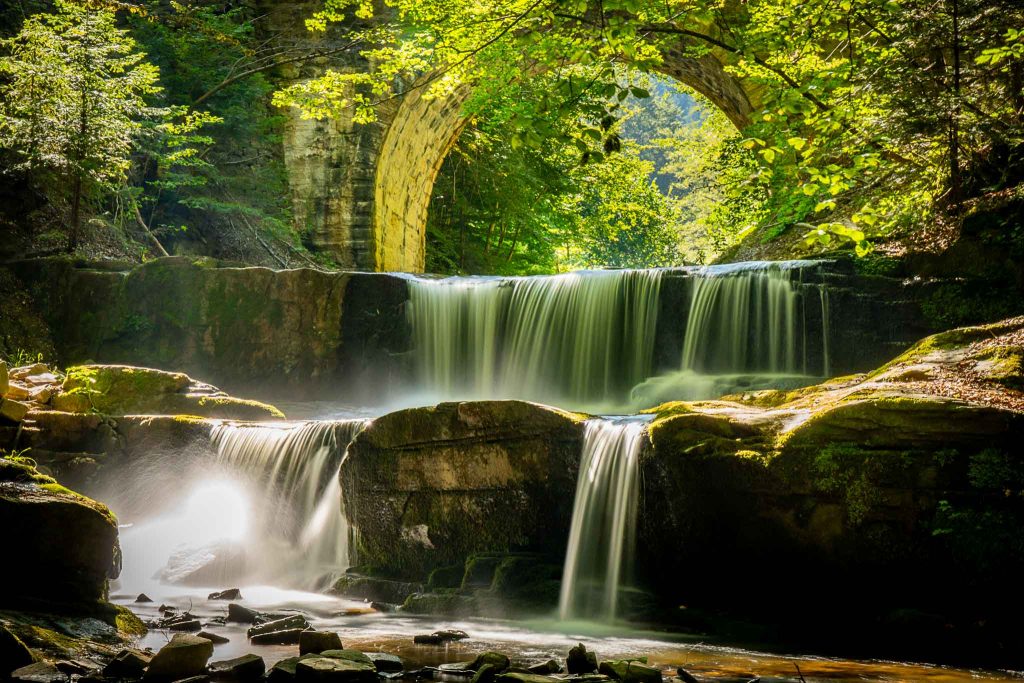 A small waterfall flowing beneath a stone bridge near Sitovo village in the Rhodope Mountains, Plovdiv region, Bulgaria.
